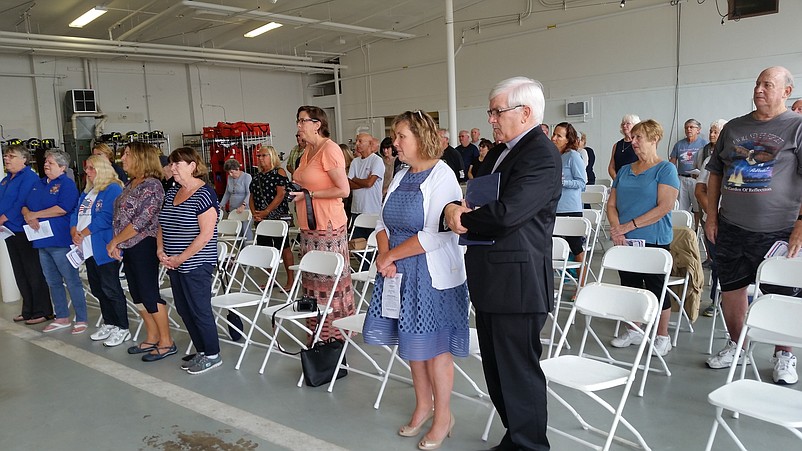 Members of the audience stand during the ceremony inside the Sea Isle fire department's headquarters for the singing of "God Bless America."