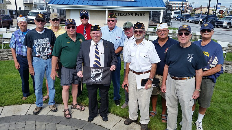 Local military veterans, led by Cape May County American Legion Commander Norman Marlin, center, holding banner, join together after the ceremony.