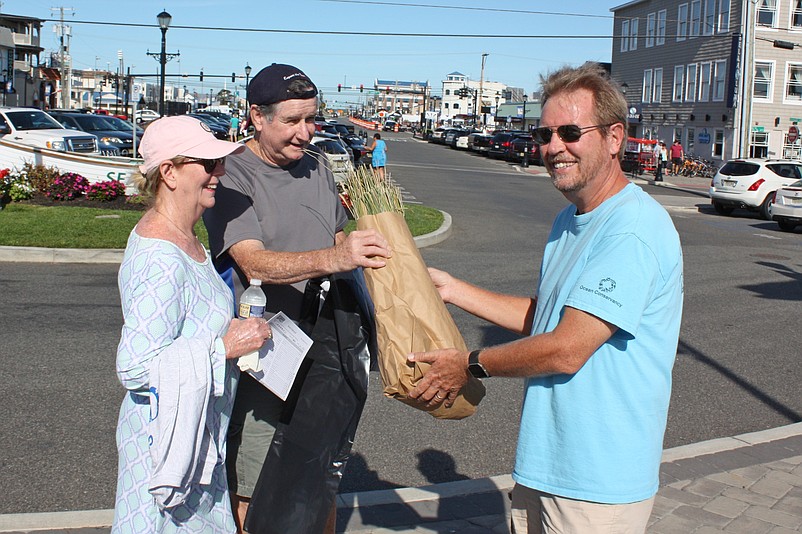 Volunteers are needed to clear debris from the beaches and plant dune grass. Shown in 2017 receiving a bag of dune grass seedlings from Environmental Commission member Steve Ahern (far right) are volunteers Mary and Jerry McManus, of Springfield, Pa., and Sea Isle City. (Photo by Sea Isle City Public Relations)