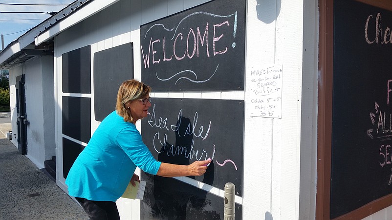 Rosemary Deery, sister of Mike's Seafood and Dock Restaurant owner Mike Monichetti, writes a welcome message for the Chamber of Commerce meeting at the eatery.