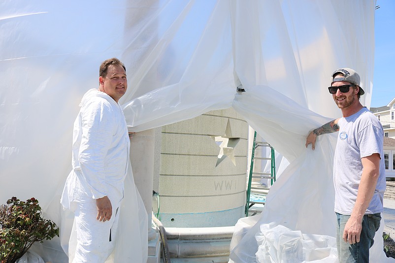 A.J. Andre, left, the owner of Andre Properties, and his employee, Rob Martinelli, give a peek of the cleaning work inside the plastic covering.