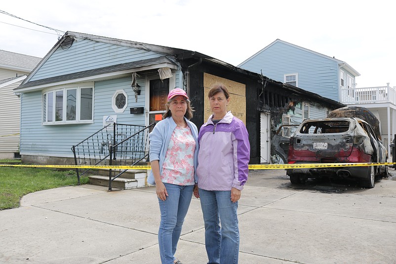 Sisters Maryann Pantano Davis, left, and Janice Pantano, stand in front of the charred remains of the vacation home on Central Avenue that their family had owned for 55 years.