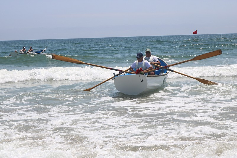 Lifeguards row ashore after honoring the deceased members of the Beach Patrol.