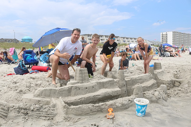 Members of the Leclair family, of Quebec, Canada, show off their elaborate sand castle.