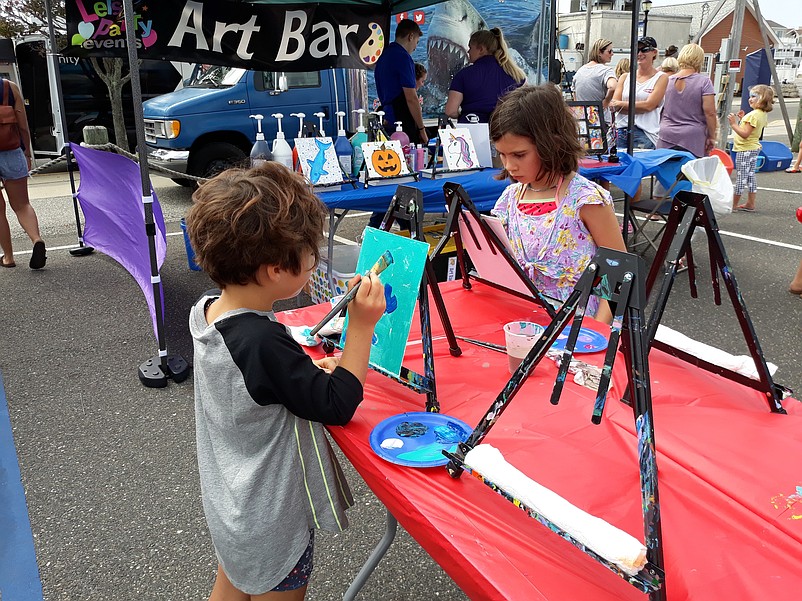 Sisters Dalila and Deanna Garcia work on their paintings at the festival's art display.