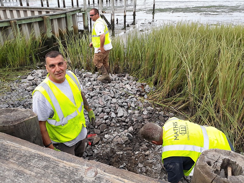 Mathis Construction Co. Inc. workers Tony Buttacavoli, left, Jerry Milano and Tom Ruf, background, put some of the finishing touches on the pumping station project.