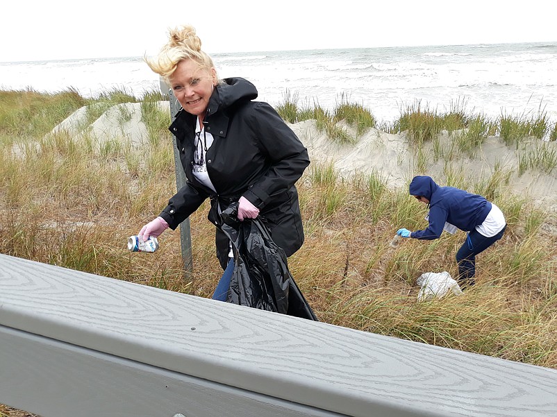 Eileen Capriotti, a sales agent at BHHS Fox &amp; Roach Realtors, picks up a discarded can from the dunes.