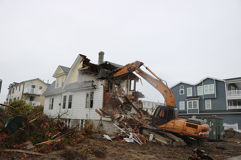 The old home is reduced to rubble by a demolition excavator. 