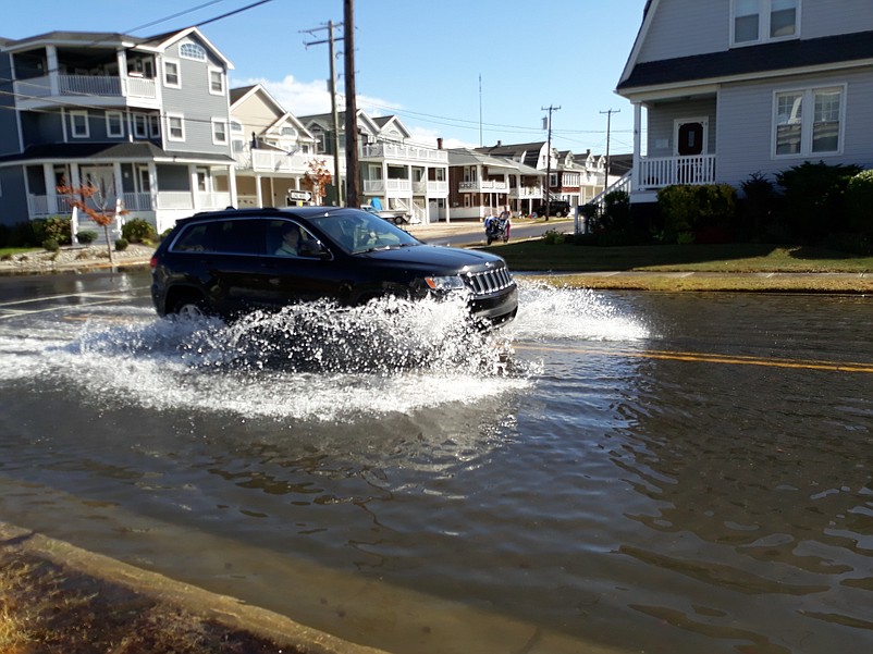 A Jeep kicks up a spray of water while passing through a flooded street in 2019.