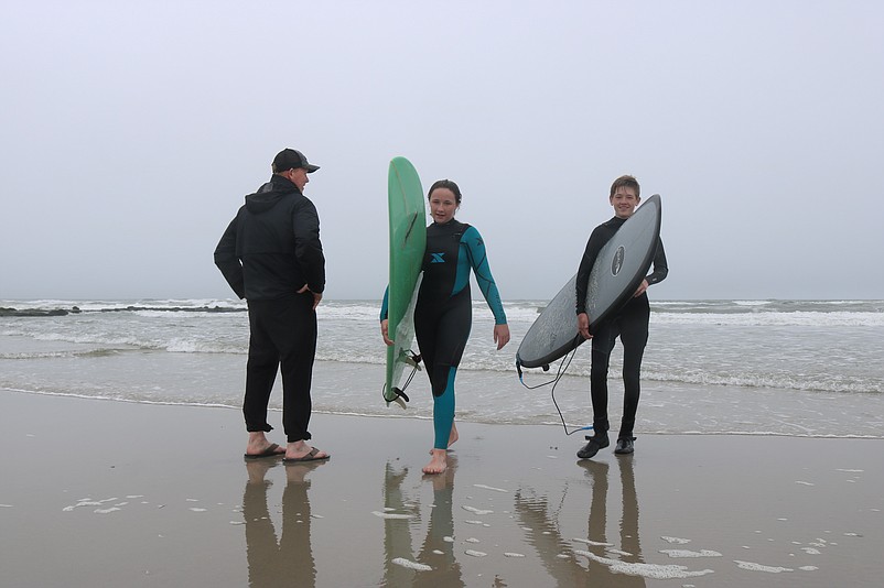 Scott Megill, of West Chester, Pa., watches his daughter, Shannon, and son, Ryan, emerge from the ocean after surfing in Sea Isle City.