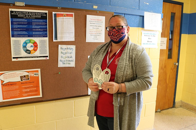 City Clerk Shannon Romano, her face covered as a precaution against the coronavirus pandemic, holds two of the highly coveted parking permits.