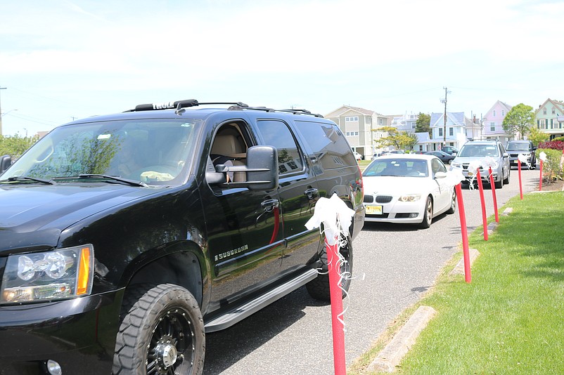 A stream of car holding graduating seniors drive around the Ocean City Tabernacle grounds.