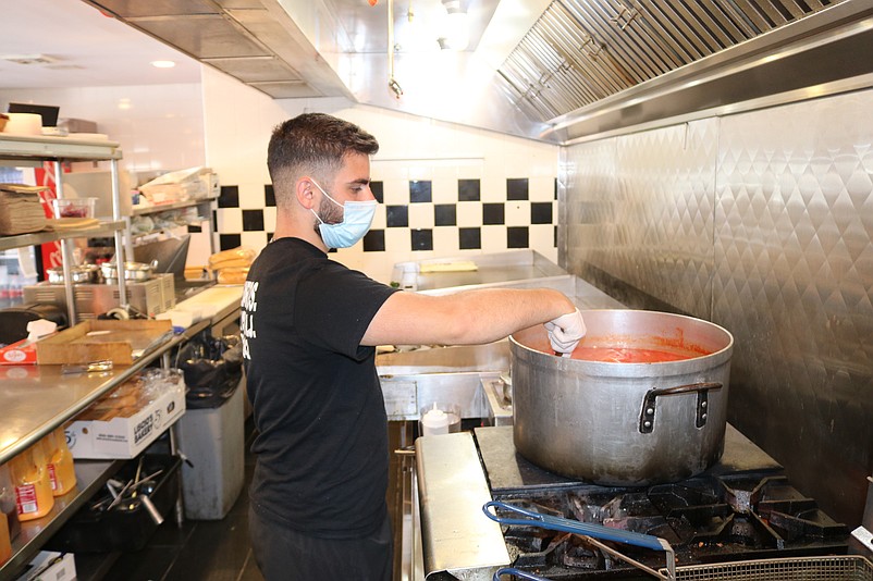 Mike Berardi stirs the homemade sauce cooking in a large pan.