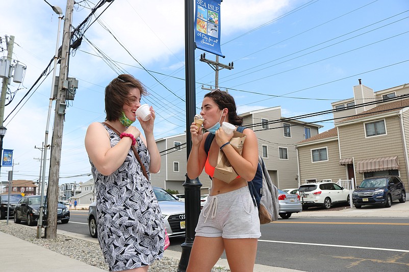 From left, sisters Brittany and Carly Lare devour their ice cream and sorbet before the treats are melted by the blazing sun.