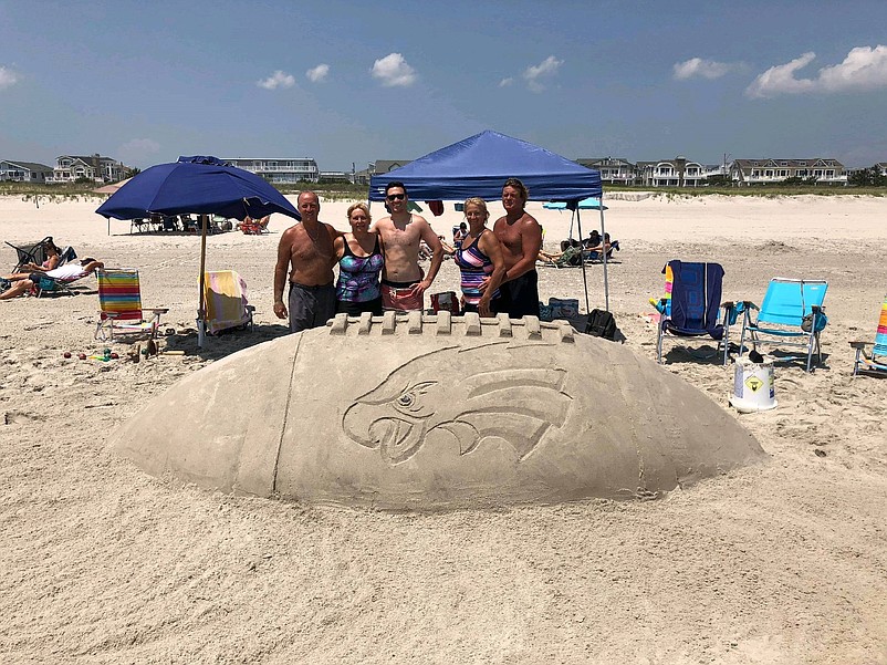 From left, Tom Deb and Michael Doyle and Jocie and Scot Schermerhorn, all of Pennsylvania, stand behind a giant sand sculpture of  a Philadelphia Eagles football.