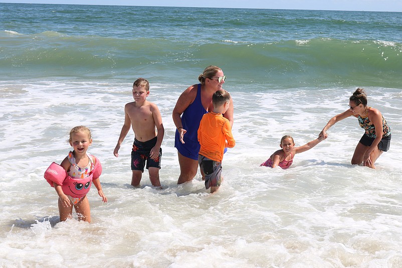 Jennifer Parker, in blue bathing suit, and Melissa Harper, right, frolic in the surf with Cassidy, 4, Jackson, 10, Chase, 8, and Maddie, 7.