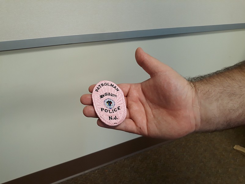 Officer Kirk Rohrer holds the pink colored police badge he will wear during Breast Cancer Awareness Month.