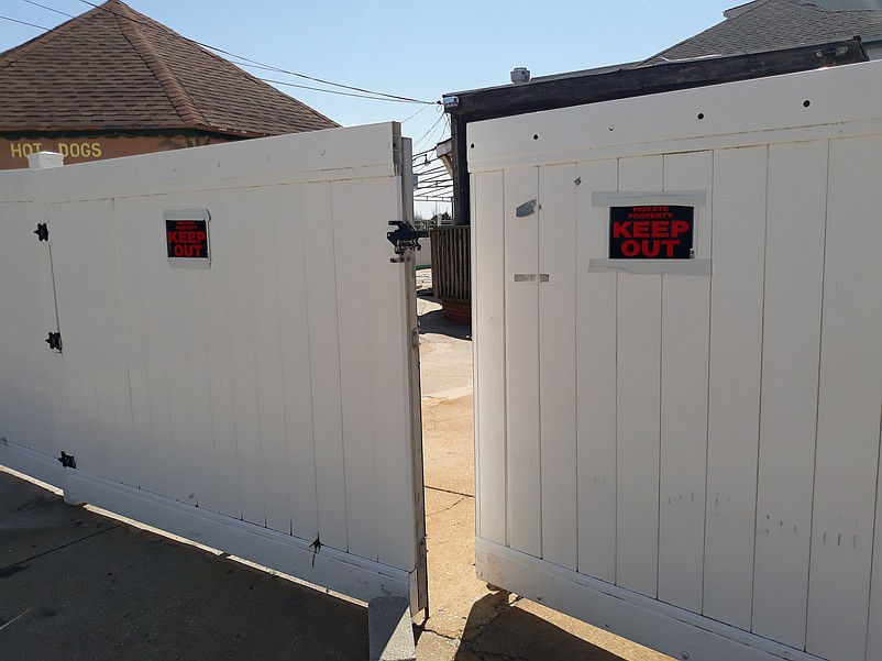 A vinyl fence and "No Trespassing" signs block access to the old Carousel Bar.