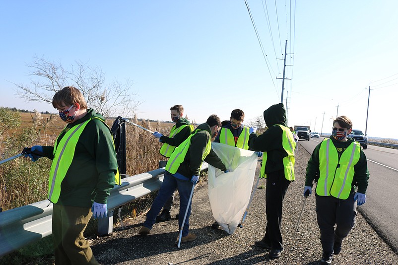 Trash bags in hand, the Boy Scouts from Troop 76 remove litter from the side of the road.