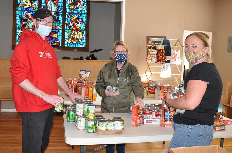 Peg Moore, center, and Tyler and Ronda Pergola, help prepare some of the Thanksgiving dinners at the United Methodist Church food bank. (Photo courtesy of Patti Lloyd)