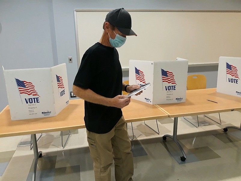 Election worker Howard Wright checks his voter records at the polling place at the Sea Isle City Library.