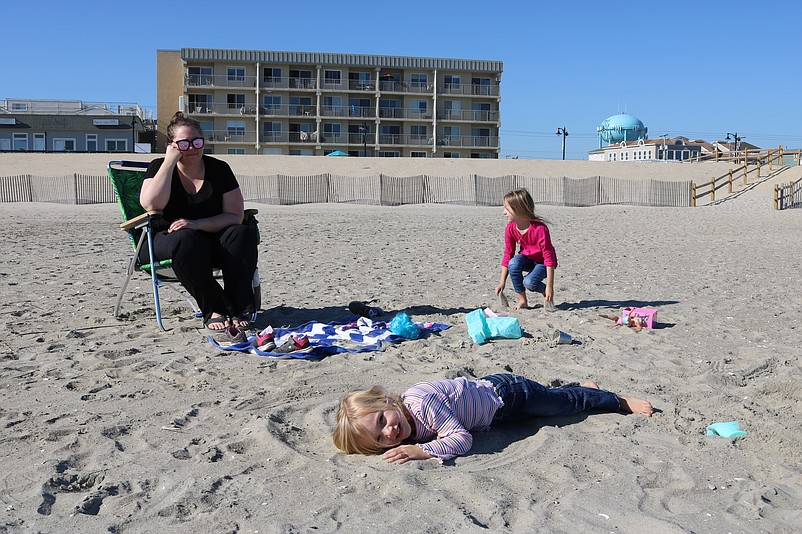 Ali Mulford watches her daughters, Bailey, 4, and Taylor, 7, play in the  sand on a spectacular beach day in November.