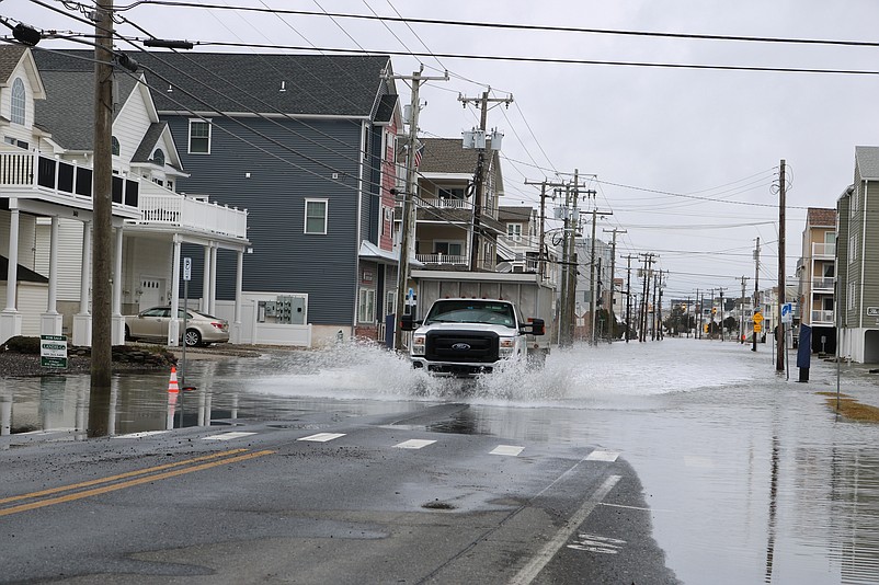 A commercial truck kicks up wakes of water while crawling through flooding on Landis Avenue.