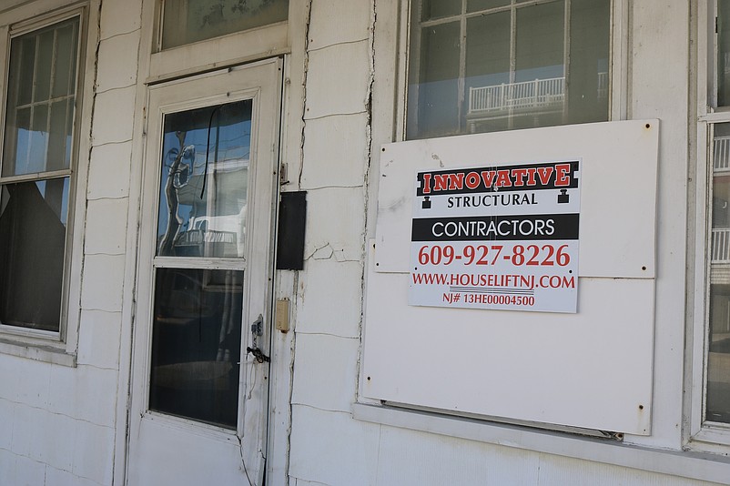 A sign by a house-lifting company indicates the original plan by the developers to possibly elevate and renovate the old home.