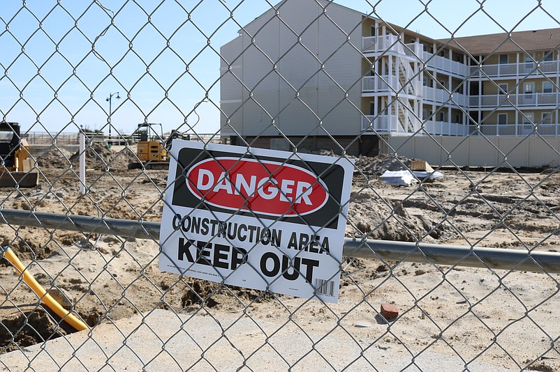 A construction fence and "Danger" signs ring the property.