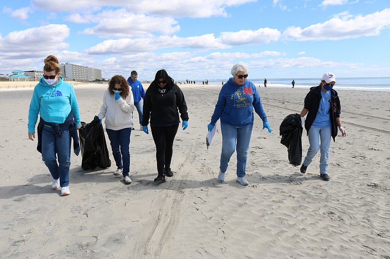 Employees from the 1st Bank of Sea Isle City walk along the beach looking for litter during the spring cleanup.