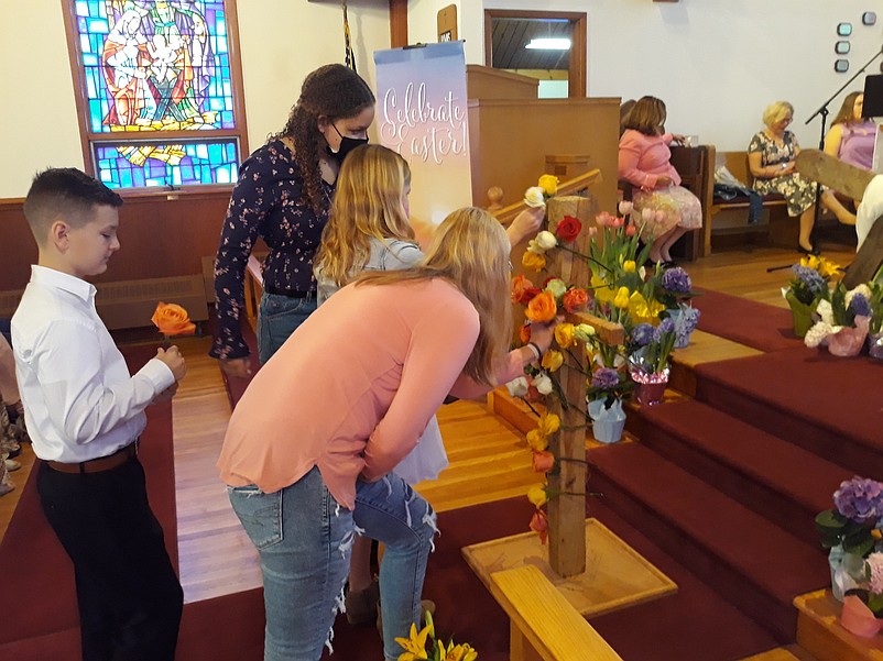 Worshippers at United Methodist Church adorn a wooden cross with roses to symbolize the beauty of Christ's resurrection.