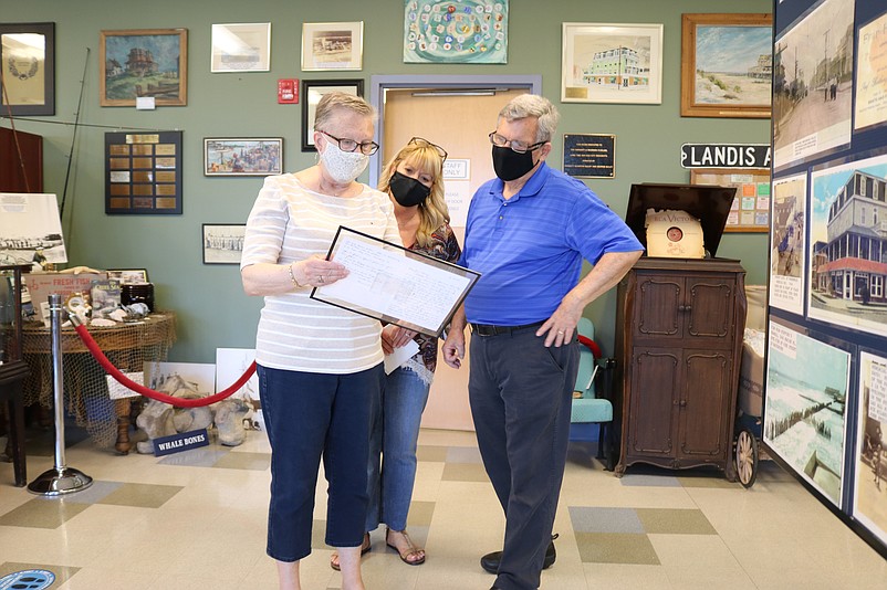 From left, museum curator Barbara McKeffery, then president Abby Powell and volunteer and new president Ron Kovatis look at a collection of old postcards in May.