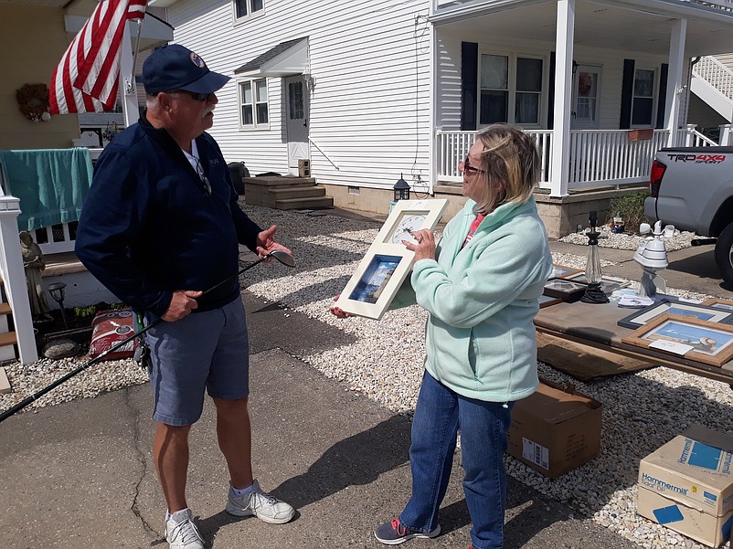 Peggy Moore shows her husband, Terry, a framed picture they have up for sale at their 58th Street home.