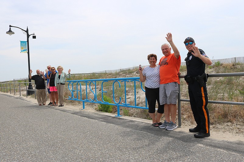 From left, Mayor Leonard Desiderio is joined by Steve and Donna Farren, of Coatesville, Pa., the city's Chief Financial Officer Paula Doll, Jane and Frank Capasso, of Sea Isle, and Officer Edward Adams next to one of the new, blue Sea Isle City signs on the Promenade.