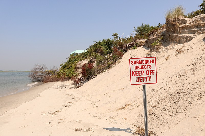 A sign warns of submerged objects where the beach is eroded.