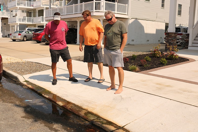 From left, Fred Caspar, Chip Laux and Tom Robinson look at the slimy water that pools in the gutter in front of their homes on 38th Street.