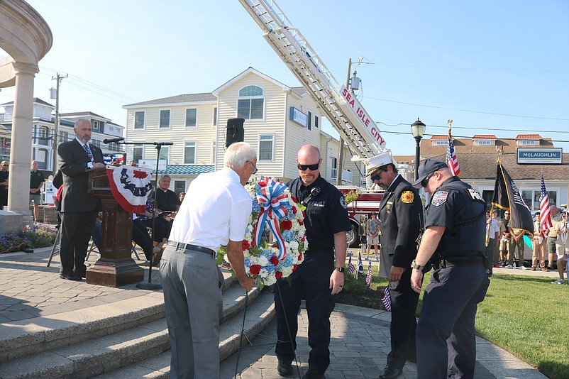 From left, VFW Post 1963 Commander Mark Lloyd accepts a wreath from Sea Isle City's EMT Chief Bruce Knoll, Fire Chief John Mazurie and Police Chief Tom McQuillen at the ceremony.