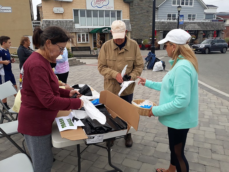 Environmental Commission member Abby Powell, right, hands out vinyl gloves and trash bags to cleanup volunteers.