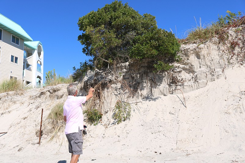 Joe Civitillo, a condominium owner at Townsend Shoals, points to dune erosion on the bay side of Townsends Inlet.