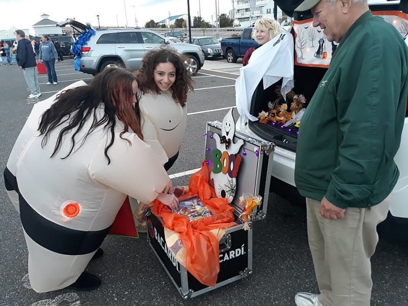 Destiny O'Donnell and Isabella Sanchez, wearing sumo wrestler costumes, select some candy offered by City Councilman William Kehner and his wife, Cheryl.