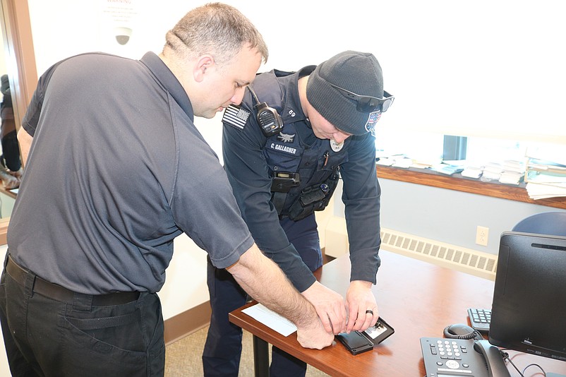 Police Dispatcher Steve Myers, left, gets his fingerprints taken by Officer Cooper Gallagher to show how the process works.