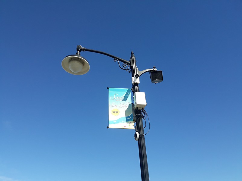 A closeup photo reveals the camera and other devices attached to the light pole.