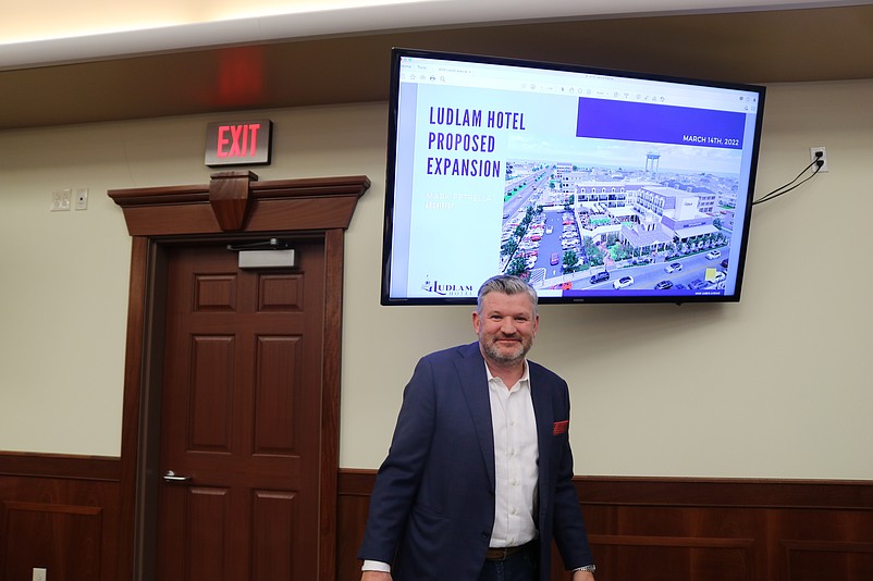 Developer Christopher Glancey stands in front of a rendering of the project displayed on a screen during the planning board meeting.