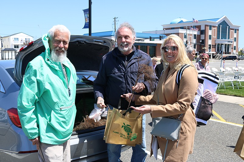 From left, Beautification Committee member Alan Nesensohn and Environmental Commission member Dudley McGinty hand out some of the tree seedlings to Sea Isle resident Beth Pearce in 2022.