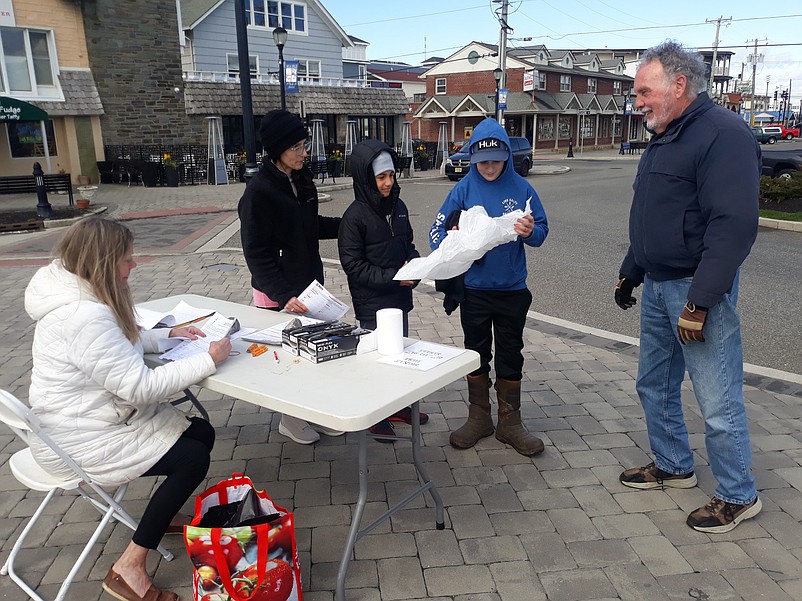 From left, beach cleanup volunteers Janice Jefferson, her son, Ryan, and his friend, Drake Williams, speak with Sea Isle Environmental Commission members Dudley McGinty and Susan Ahern, seated.