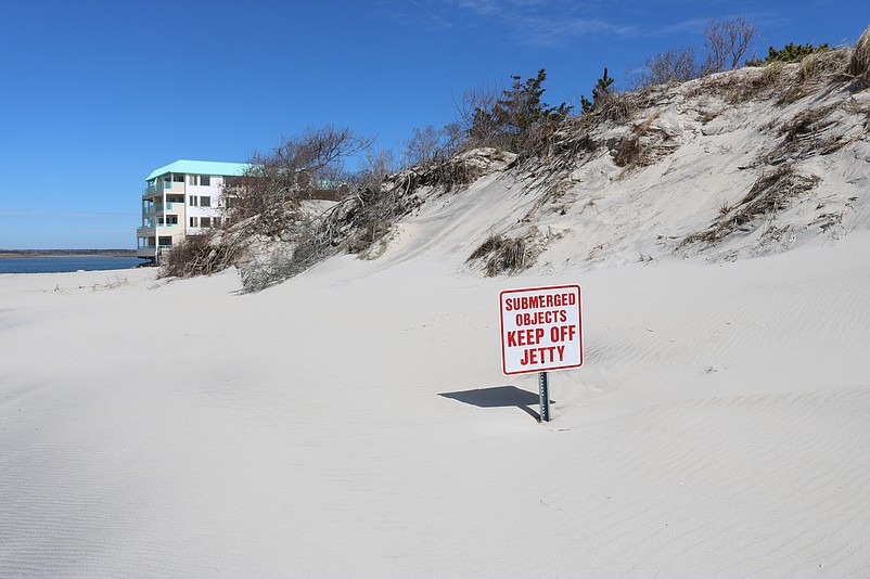 This sign now barely pokes out of the beach because the base has largely been buried in new sand.