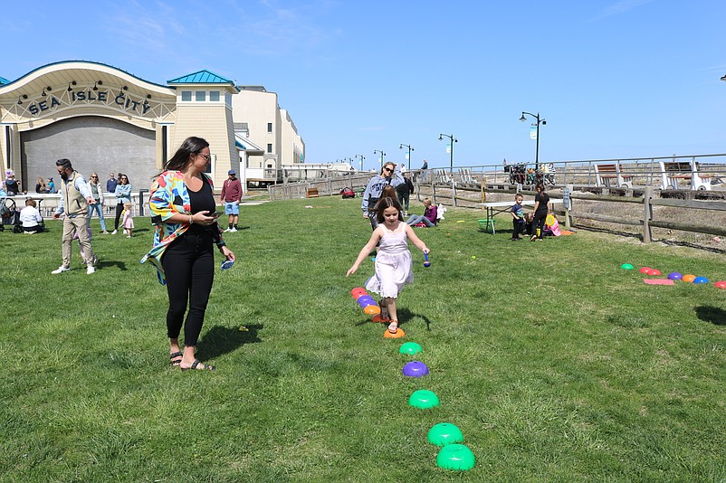 Kids run in the grass at Excursion Park while playing a game of spoon and egg racing.