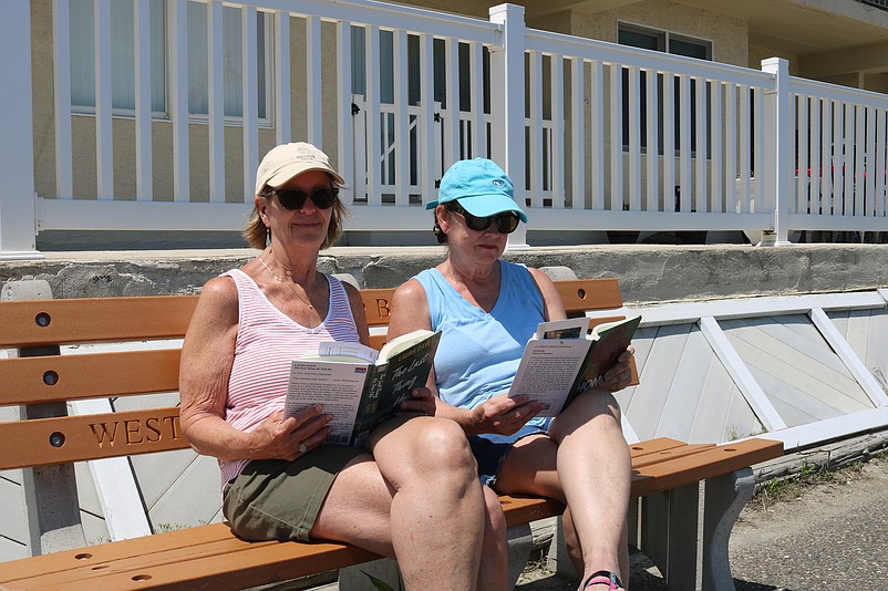 Sisters-in-law Cathy Gillen, left, and Noreen Gillen enjoy their books while sitting on a bench on the Promenade.