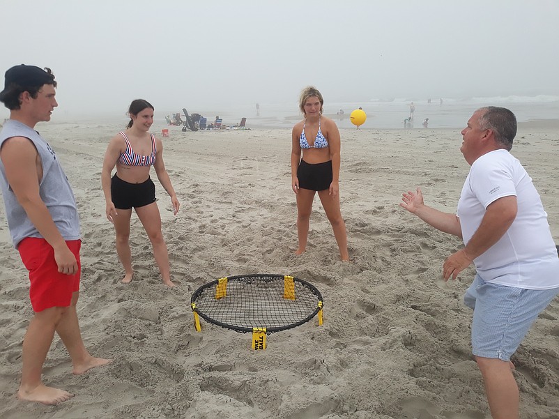 Kevin Bryant, right, plays a game of Spike Ball on the foggy beach with his son, Aidan, family friend, Gianna Vallone, and his daughter, Kelsey, to kick off the Memorial Day weekend.