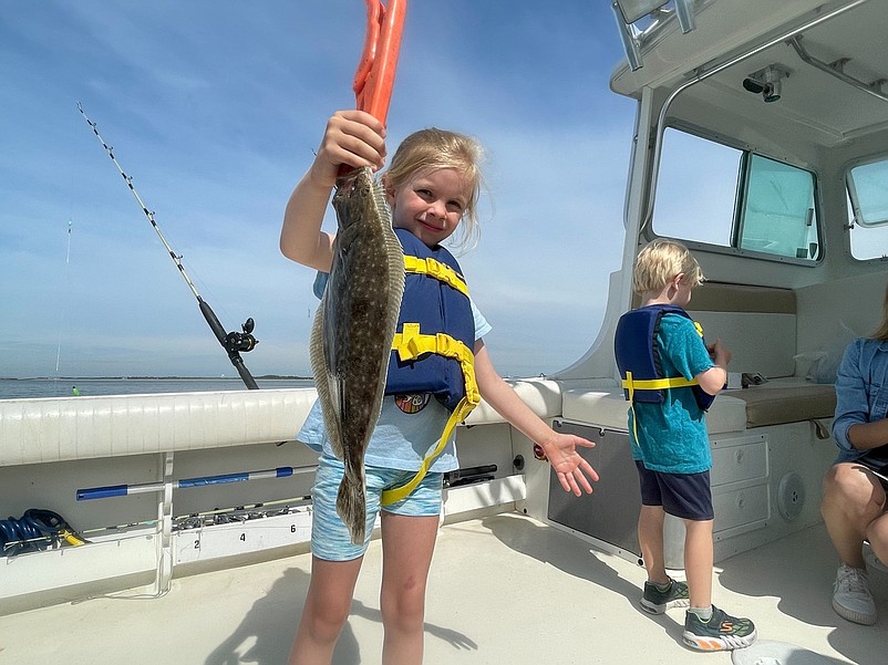 A little girl shows off a flounder caught during a Mighty Heron Charters fishing trip. (Photo courtesy of Mighty Heron Charters)